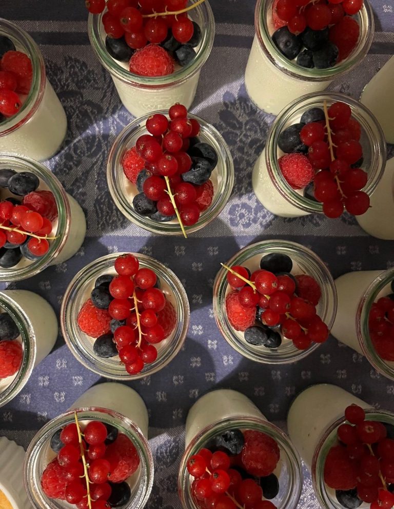 Zitronen-Mousse mit frischen Beeren-Topping Dessert im Glas mit Creme, roten Johannisbeeren, Heidelbeeren und Erdbeeren.