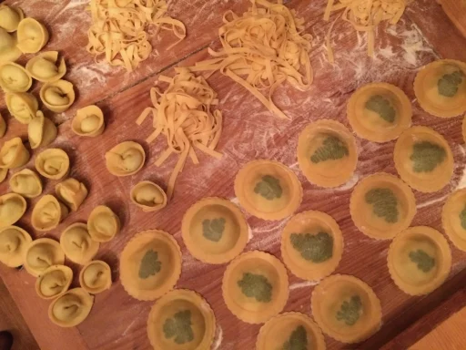 Verschiedene frische Pastaformen auf einer bemehlten Arbeitsfläche.