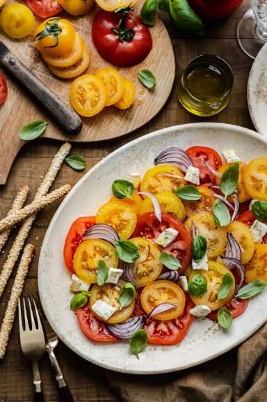 Bunter Tomatensalat mit roten und gelben Tomaten, roten Zwiebeln, Käse und Basilikum.